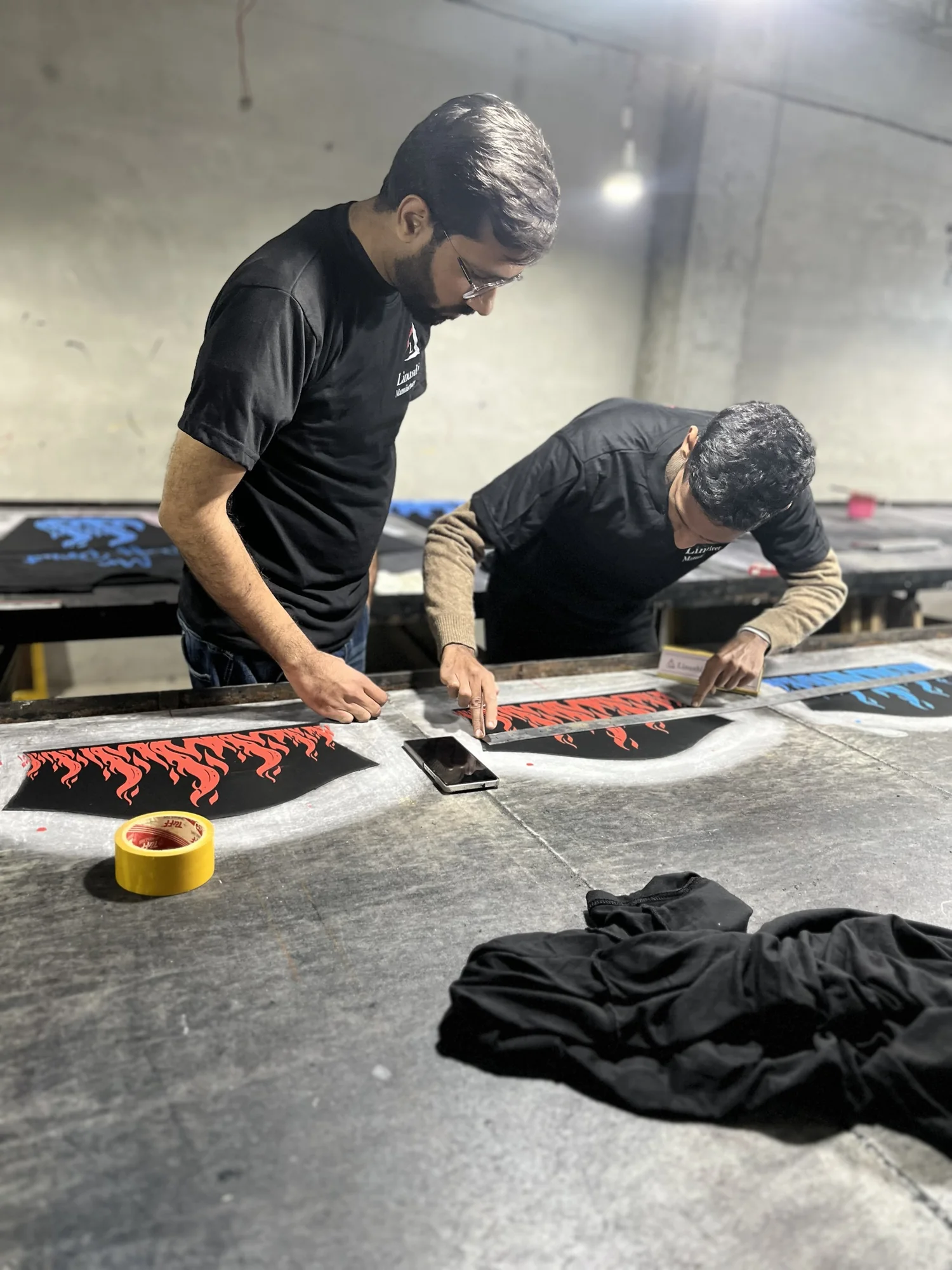 Two Linushi workers measuring print placement on hoodie panels