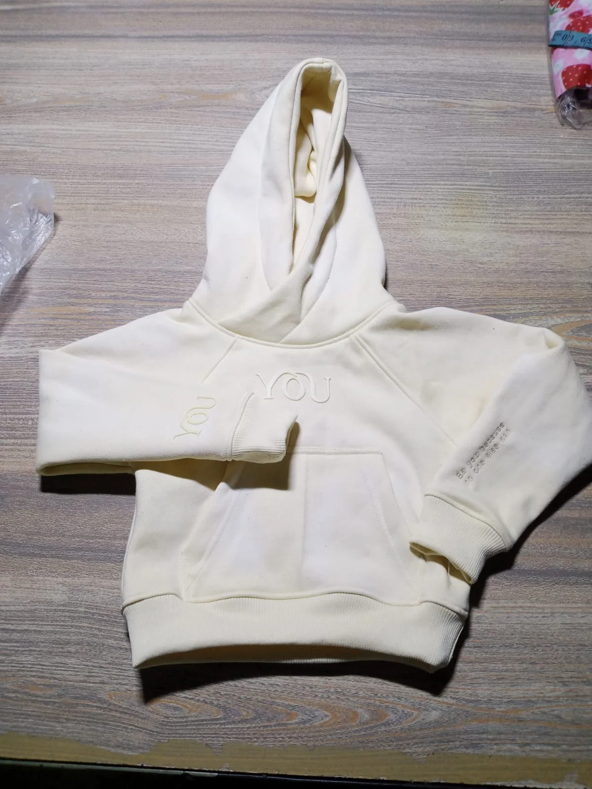 Cream hoodie laid flat with sleeve prints