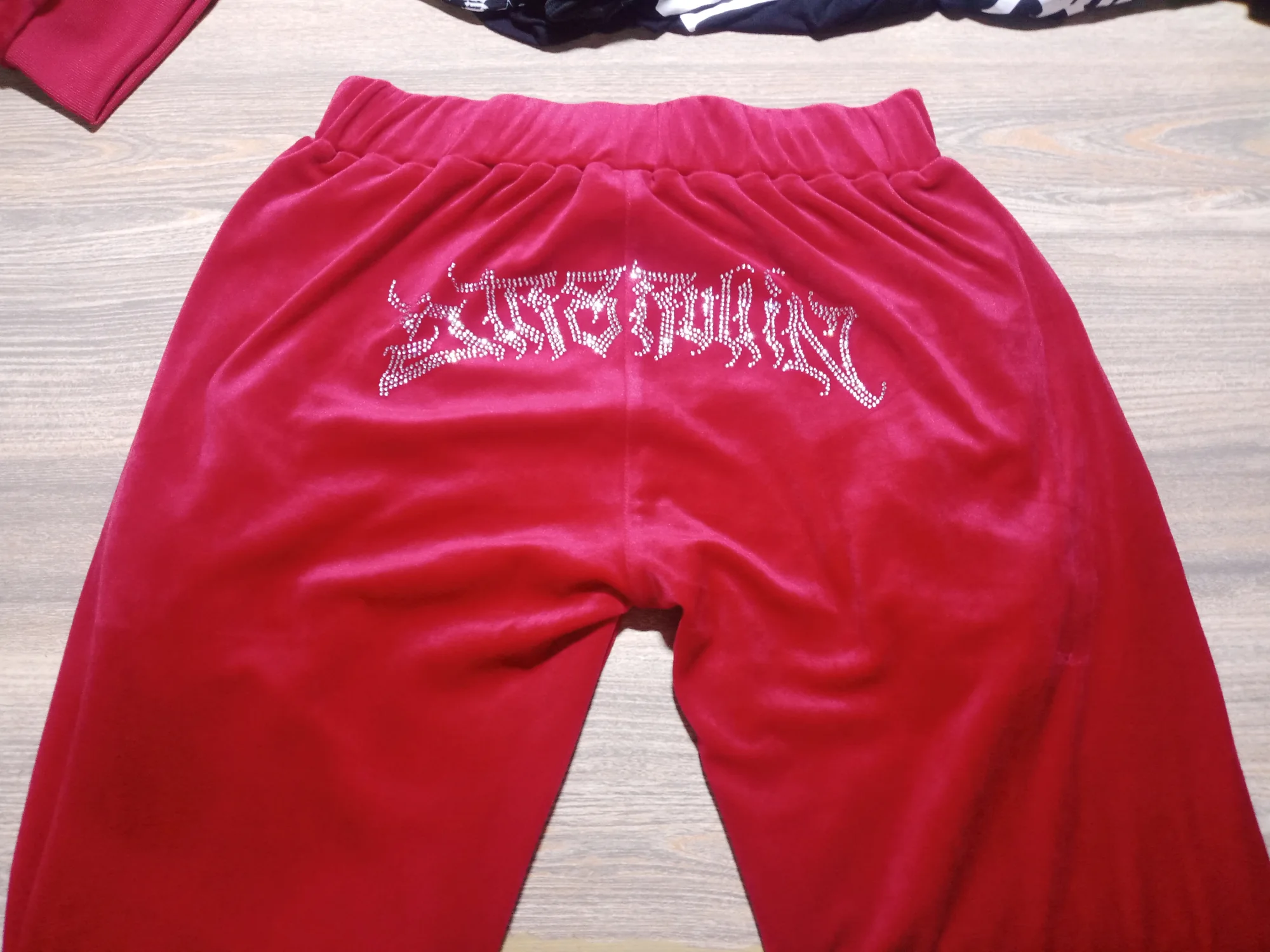 Red velour pants with rhinestone lettering on the back