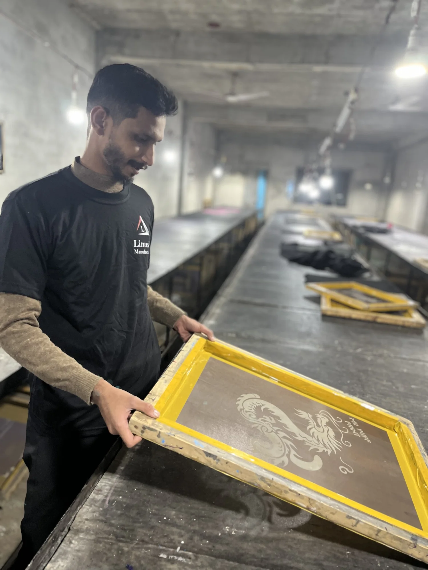 Worker holding a dragon puff print screen at the Linushi factory
